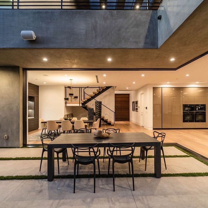 Moderner Gartenbereich einer Luxusvilla mit Esstisch und Blick ins Wohnzimmer